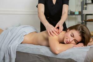 profesional masajista haciendo terapéutico masaje. mujer disfrutando masaje en su hogar. joven mujer consiguiendo relajante cuerpo masaje. foto