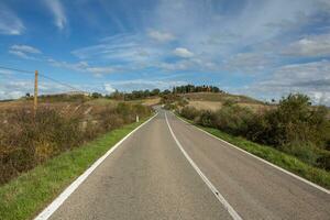 Famous Tuscany landscape with curved road and cypress, Italy, Europe. Rural farm, cypress trees, green field, sunlight and cloud. photo