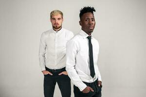 Friends. Two guys in white shirts and dark pants posing in the studio on a white background photo