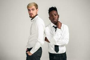 Friends. Two guys in white shirts and dark pants posing in the studio on a white background photo