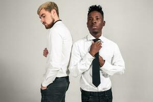 Friends. Two guys in white shirts and dark pants posing in the studio on a white background photo