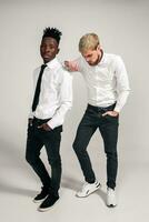 Friends. Two guys in white shirts and dark pants posing in the studio on a white background photo