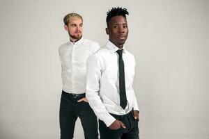 amigos. dos chicos en blanco camisas y oscuro pantalones posando en el estudio en un blanco antecedentes foto