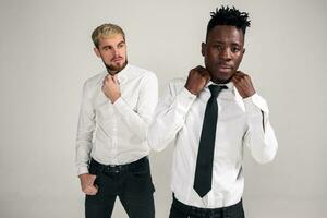 Friends. Two guys in white shirts and dark pants posing in the studio on a white background photo