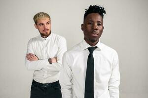 Friends. Two guys in white shirts and dark pants posing in the studio on a white background photo