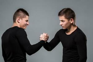 Portrait of young twin brothers standing face to face on gray ba photo