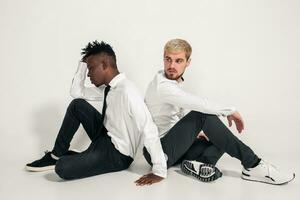 Friends. Two guys in white shirts and dark pants posing in the studio on a white background photo