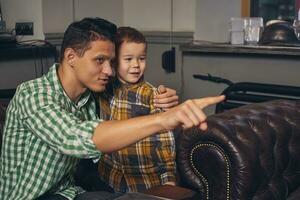 Young father and his stylish little son in the barbershop in the waiting room. photo