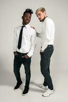 Joyful relaxed african and caucasian boys in white and black office clothes laughing and posing at white studio background with copy space photo