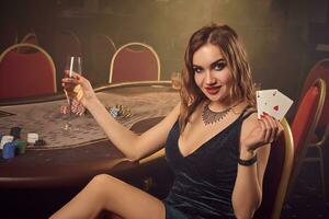 Young beautiful female is posing sitting on a chair against a poker table in luxury casino. photo