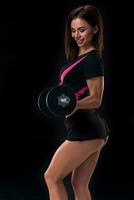 Fit body of beautiful, healthy and sporty woman with a dumbbells. Slim woman posing in sportswear. photo