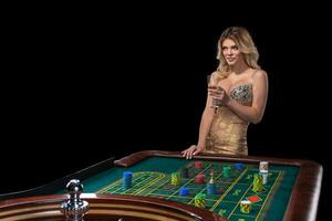 Young blonde woman wearing beautiful sexy shiny dress is playing roulette in the casino photo