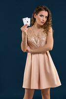Young woman holding playing cards against dark background. Studio shot photo