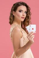Young beautiful woman holding the winning combination of poker cards on pink background. Two aces photo