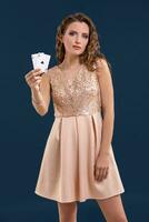 joven hermosa mujer participación el victorioso combinación de póker tarjetas en oscuro azul antecedentes. dos ases foto