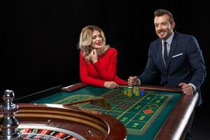 Beautiful and well dressed couple playing roulette in the casino photo