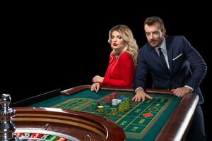 Beautiful and well dressed couple playing roulette in the casino photo