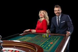 Beautiful and well dressed couple playing roulette in the casino photo