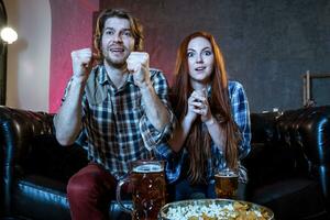 Young couple cheering for a sport team watching sports on TV photo