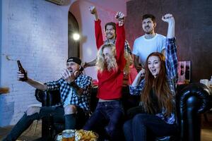 amigos acecho un fútbol americano partido y Bebiendo cerveza. foto