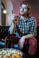 Young supporter man watching football game on television sitting photo