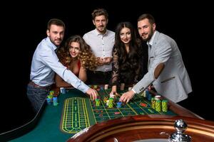 Group of young people behind roulette table in a casino photo