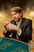 A man in a business suit sitting at the game table. Male player. Passion, cards, chips, alcohol, dice, gambling, casino - it is as male entertainment. photo