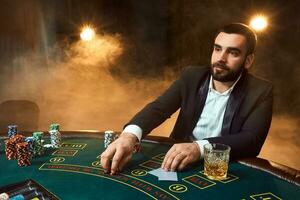un joven hombre en un negocio traje sentado a el póker mesa. hombre apuestas. el jugador a el juego de azar mesa jugando tarjetas foto