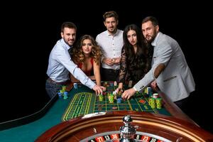 Group of young people behind roulette table in a casino photo