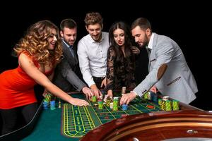 grupo de joven personas detrás ruleta mesa en un casino foto