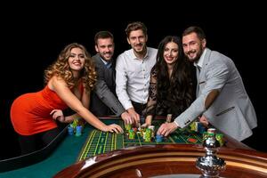 grupo de joven personas detrás ruleta mesa en un casino foto