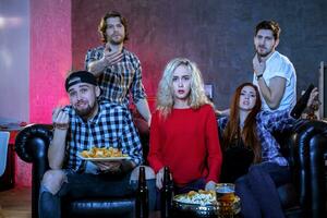 Five cheerful friends hanging out in an apartment and watching a photo