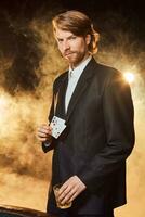 A man in a business suit standing near the game table. Male player. Passion, cards, chips, alcohol, dice, gambling, casino - it is as male entertainment. photo