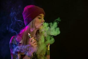 Vaping girl. Young hipster woman vape e-cig on black background. Hip-hop style. Studio shot photo