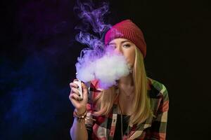 Vaping girl. Young hipster woman vape e-cig on studio on black background. Hip-hop style. Close up. photo