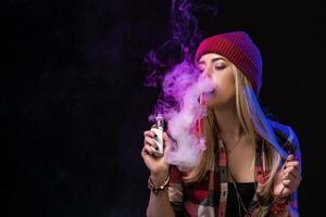 Vaping girl. Young hipster woman vape e-cig on studio on black background. Hip-hop style. Close up. photo