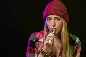 vaping muchacha. joven hipster mujer vape e-cig en estudio en negro antecedentes. hip hop estilo. cerca arriba. foto