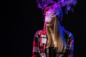 vaping muchacha. joven hipster mujer vape e-cig en estudio en negro antecedentes. hip hop estilo. cerca arriba. foto