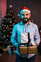 Christmas, x-mas, New year, winter, happiness concept - smiling man in santa helper hat with gift boxes photo