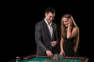 Elegant couple at the casino betting on the roulette, on a black background photo