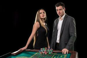 elegante Pareja a el casino apuesta en el ruleta, en un negro antecedentes foto