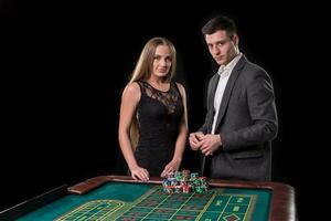 elegante Pareja a el casino apuesta en el ruleta, en un negro antecedentes foto