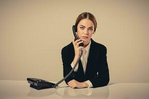 attractive dark-haired woman dressed in a black suit is sitting photo