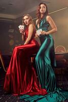 Two beautiful women are posing against a poker table in luxury casino. photo