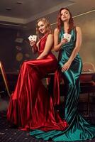Two beautiful women are posing against a poker table in luxury casino. photo