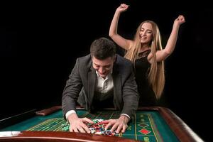 Young beautiful couple takes their winnings at the roulette table at the casino photo