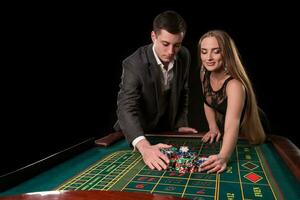 Young beautiful couple takes their winnings at the roulette table at the casino photo