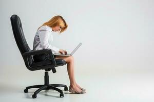 young woman sitting on the chair and using laptop photo