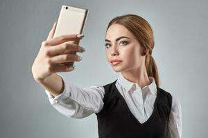 Portrait of young caucasian business woman in suit doing selfie on the phone. photo