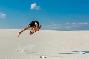 Portrait of young parkour man doing flip or somersault on the sand. photo